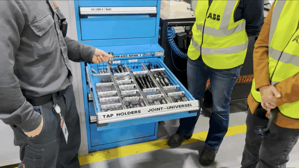 Participants en dossards ABB devant une armoire d’outillage lors de la visite de l’usine
