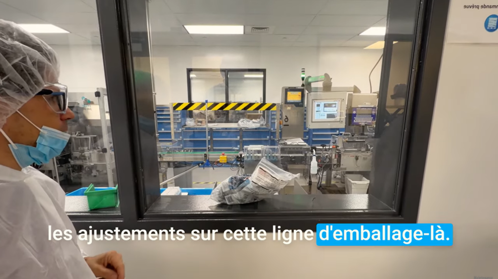 Ligne d’emballage de Pharmascience vue à travers une vitre pendant la visite d’usine
